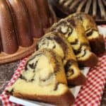 Four slices of marble cake on a white plate next to its baking pan.