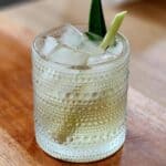 A glass of lemongrass drink on a wooden tray.