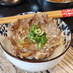 Steamed ground pork patty on top of a bowl of rice with chopsticks.
