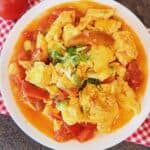 A plate of tomato egg stir fry on red and white napkin.