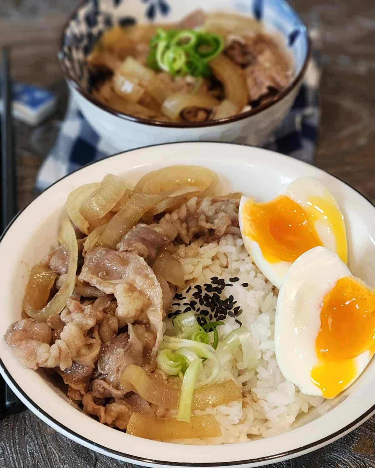 A bowl of Yoshinoya Gyudon Beef with soft-boiled egg with chopsticks. 