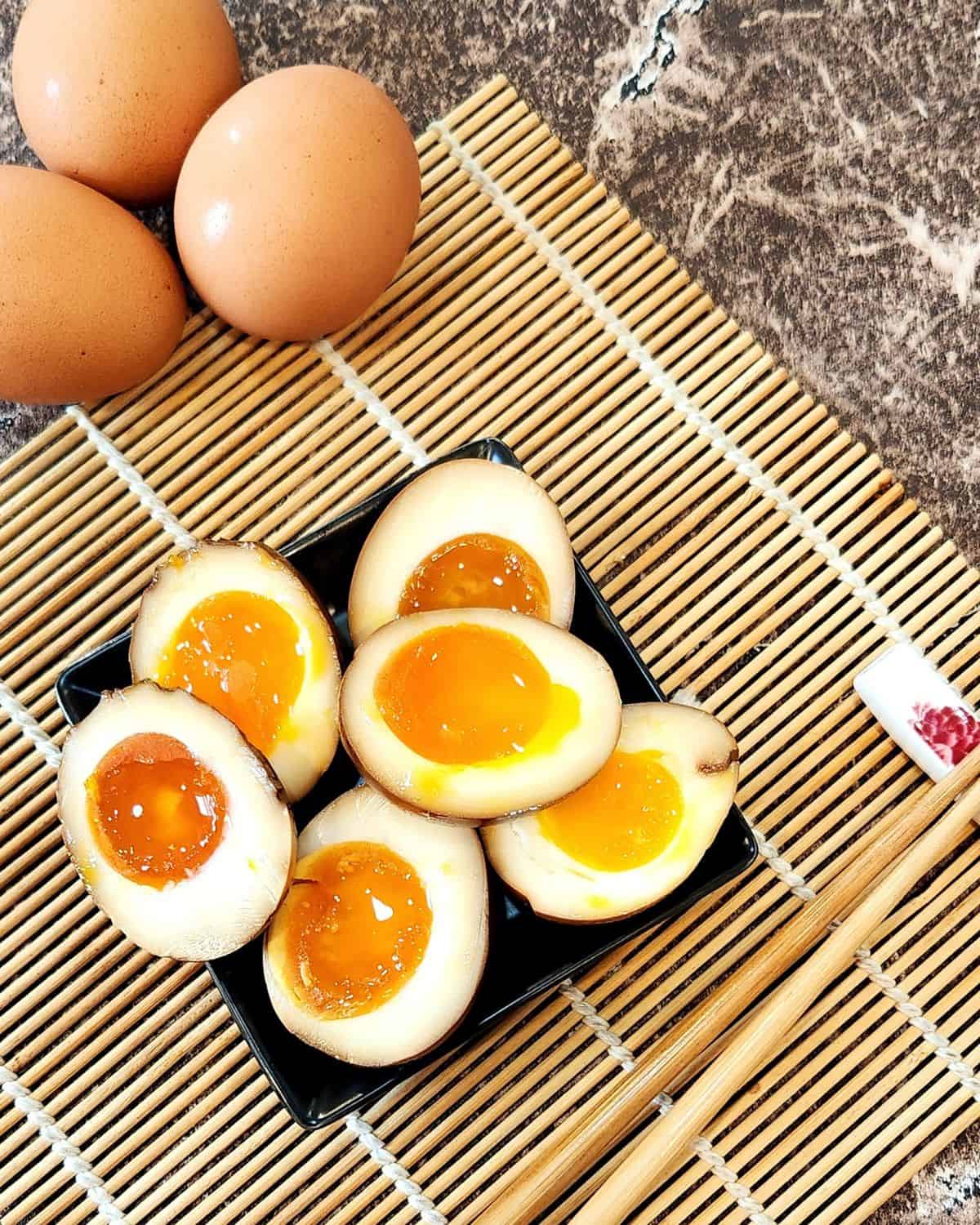 Several ramen eggs on a plate as side dish with chopsticks next to the plate.