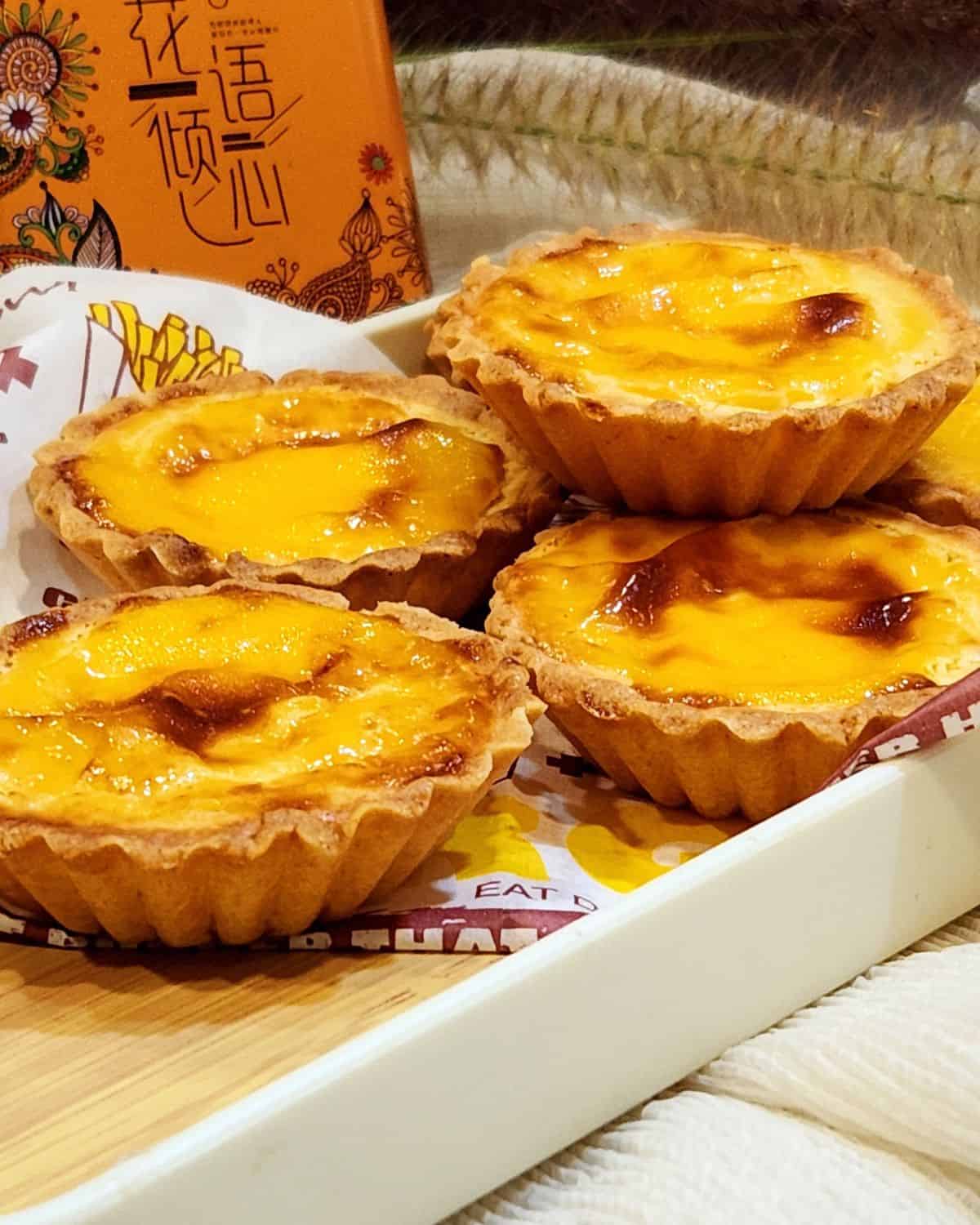 A few Hokkaido cheese tarts stacked on a wooden tray.