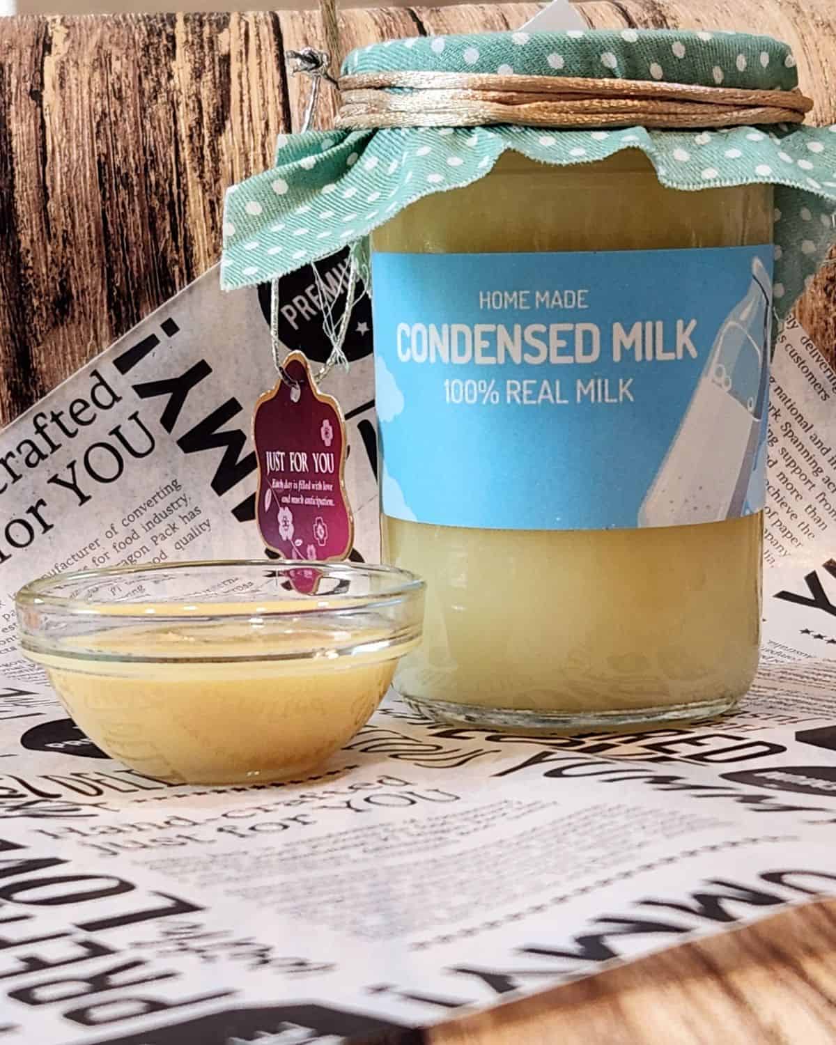A photo of homemade sweetened condensed milk in a jar and a small cup.