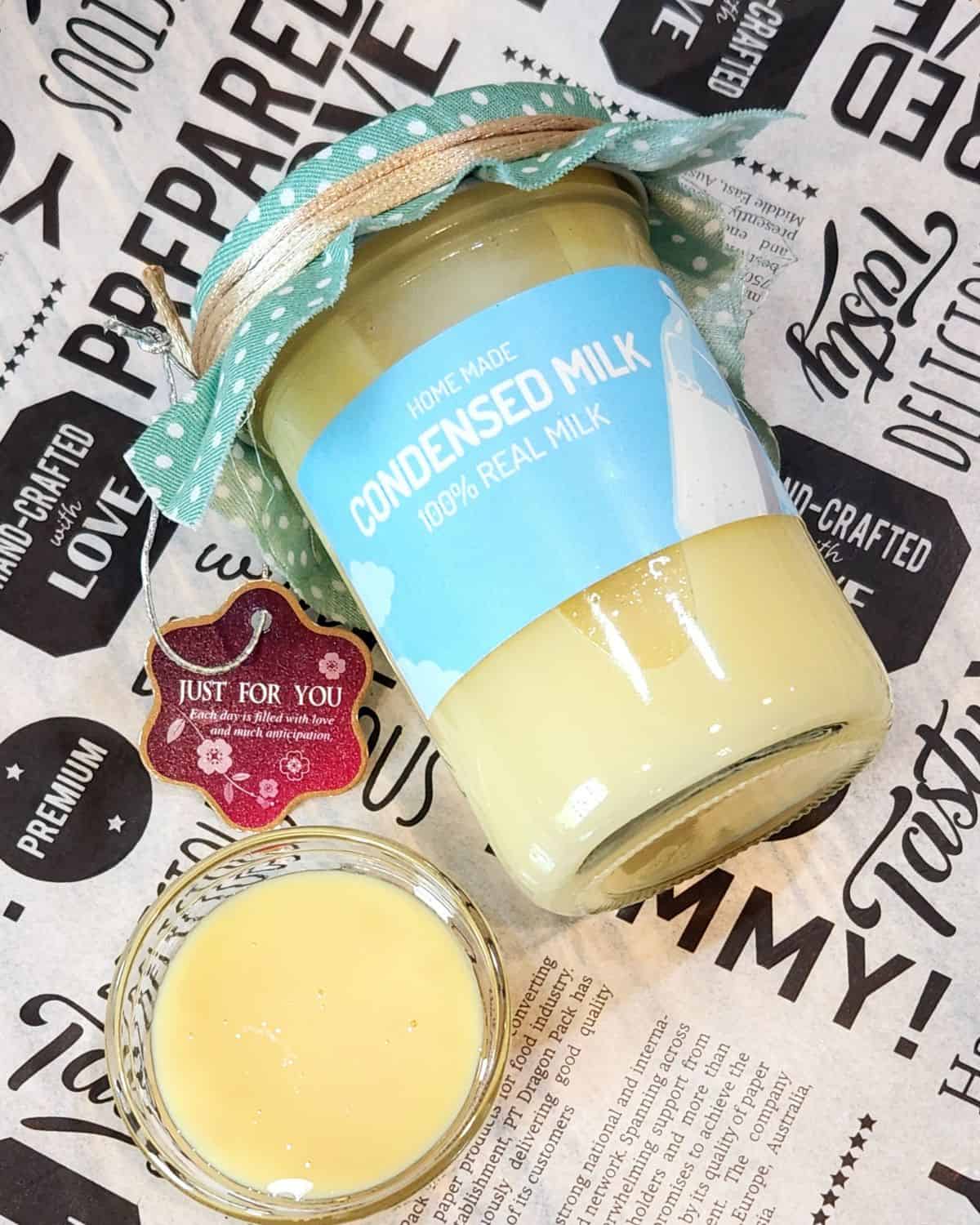 A jar of homemade sweetened condensed milk with a small cup next to it.