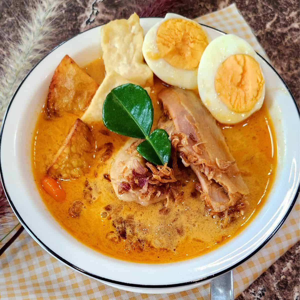 A bowl of Kari Ayam with boild eggs and fried tofus.