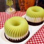Two small avocado chocolate puddings on a white plate on red and white cloth.