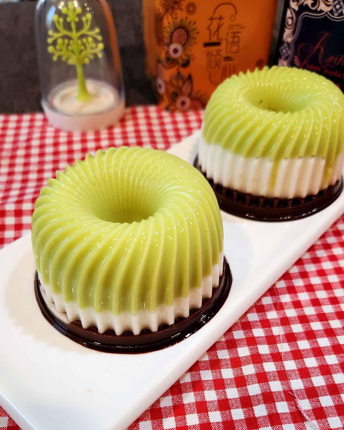 Two triple layer avocado chocolate pudding on a white plate and red white table cloth.
