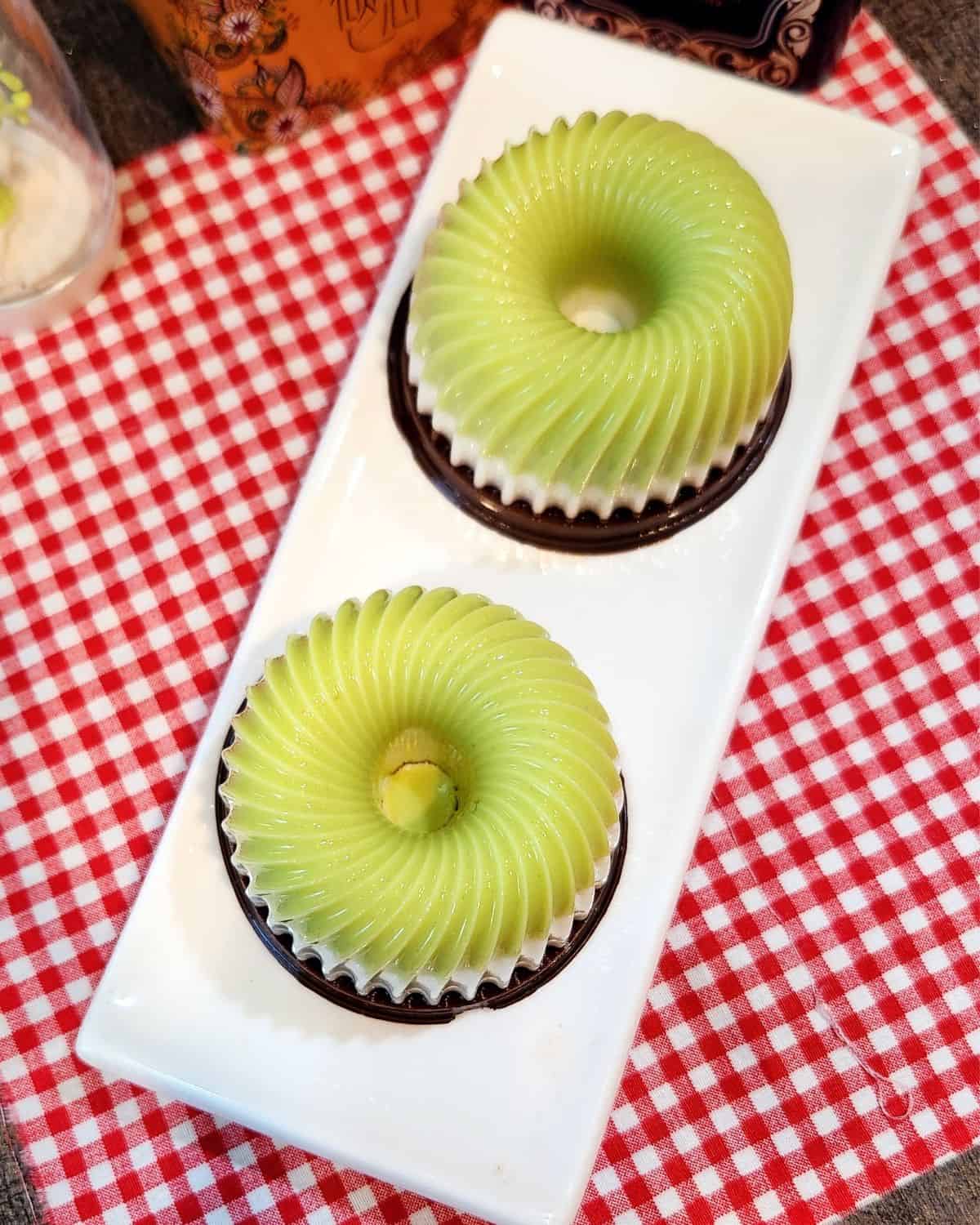 Two small avocado chocolate puddings on a white plate on red and white cloth.