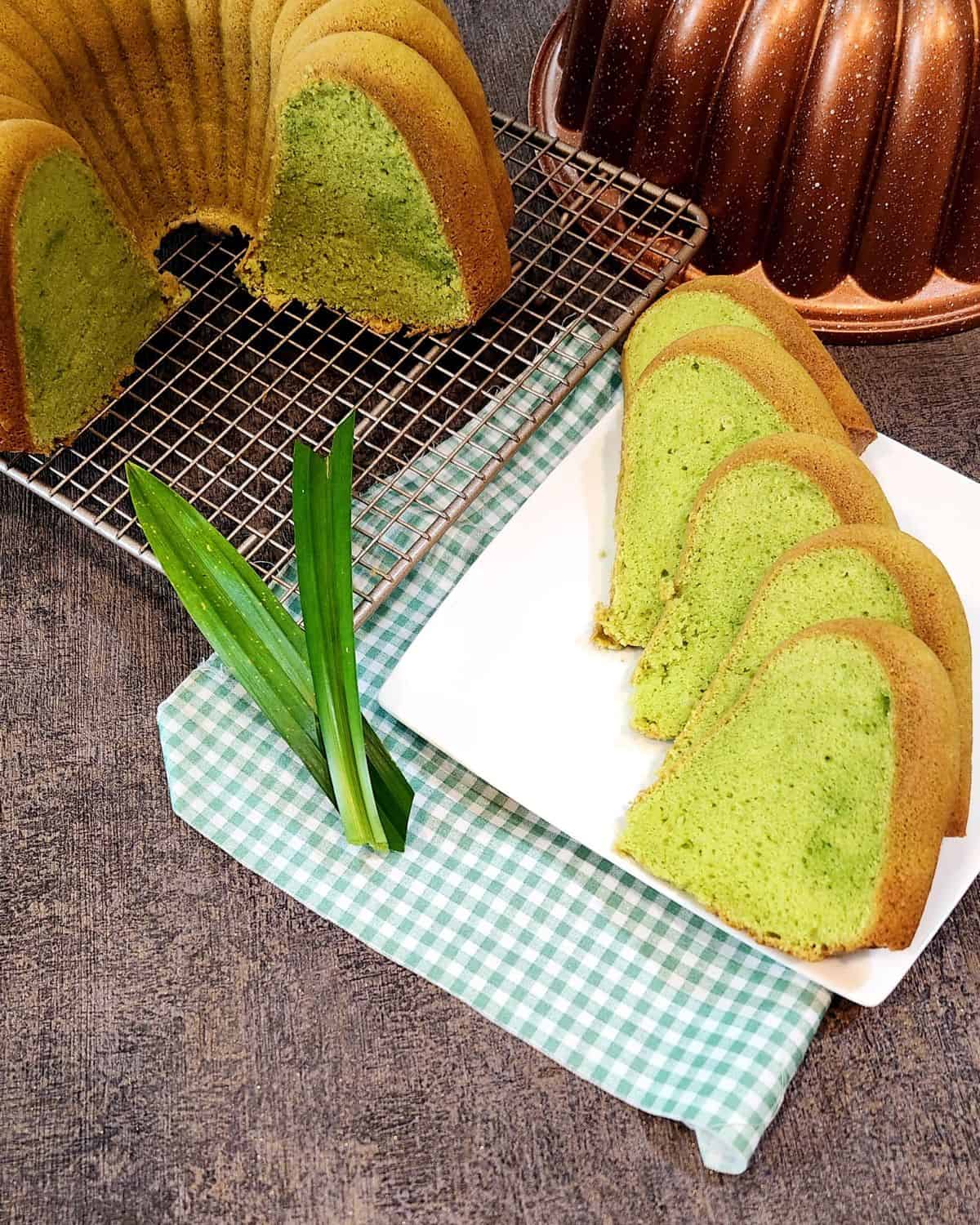 Pandan Cake slices on a white plate next to a few pandan leaves.