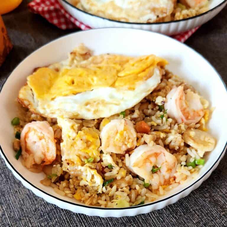 A plate of chicken and shrimp fried rice with fried egg on top.