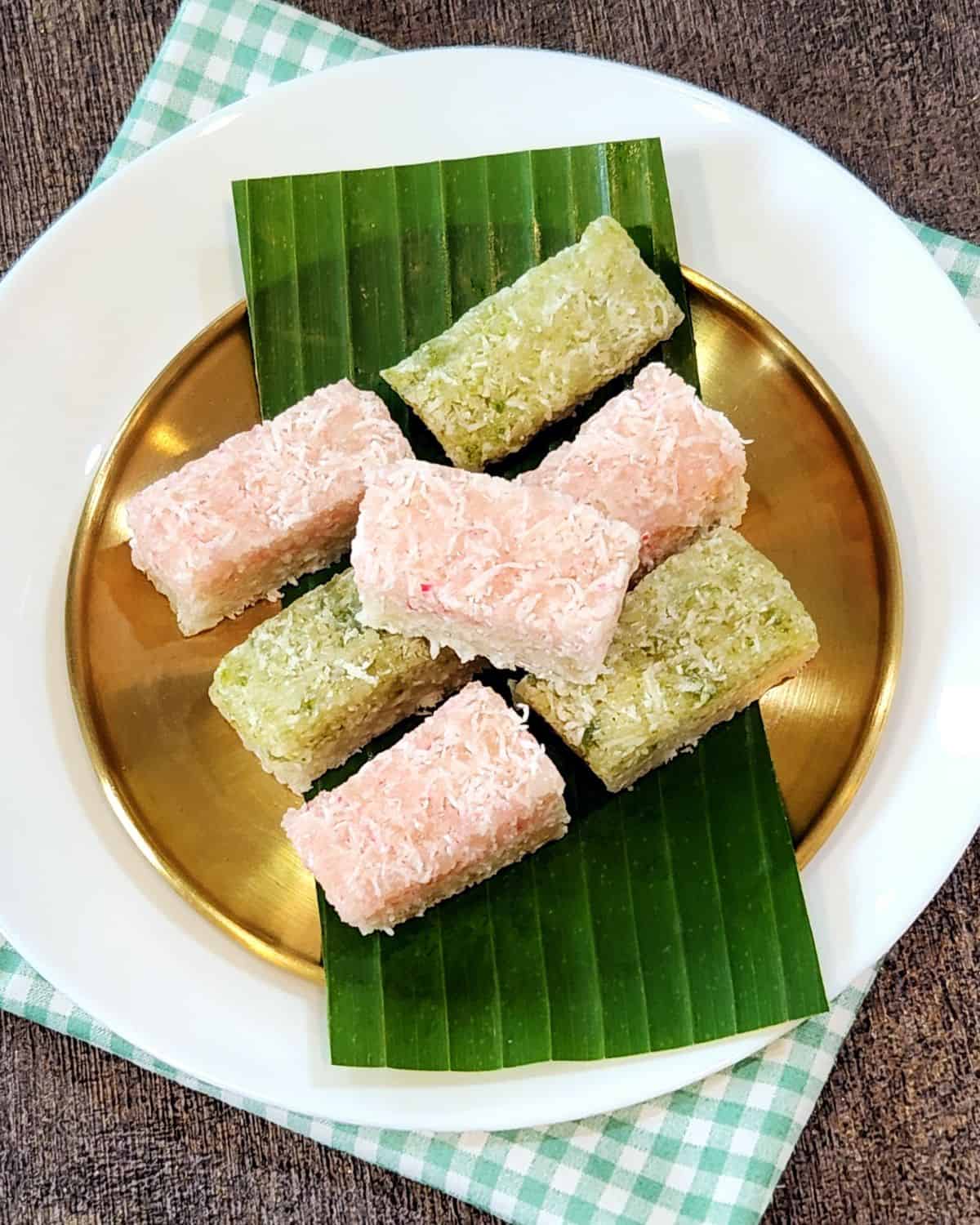 A few slices of Kue Awuk with two colors on banana leaves and golden plate.