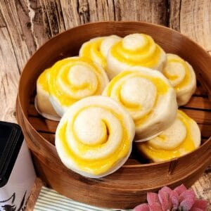 Chinese steamed bun with Cheese filling piled on a bamboo steamer.