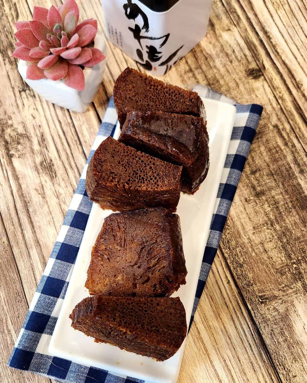 Malaysian honeycomb cake slices or kek sarang semut on a white, rectangular plate on a wooden table.
