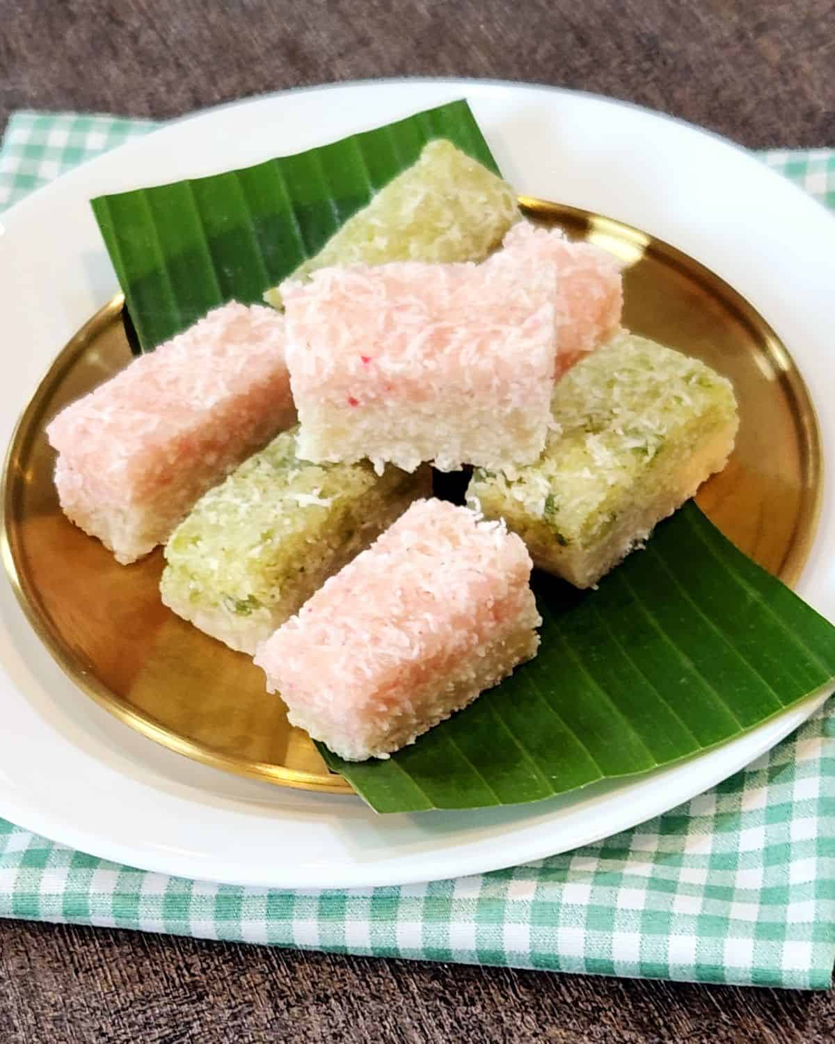 A few slices of Kue Awuk with two flavors on banana leaves and golden plate.