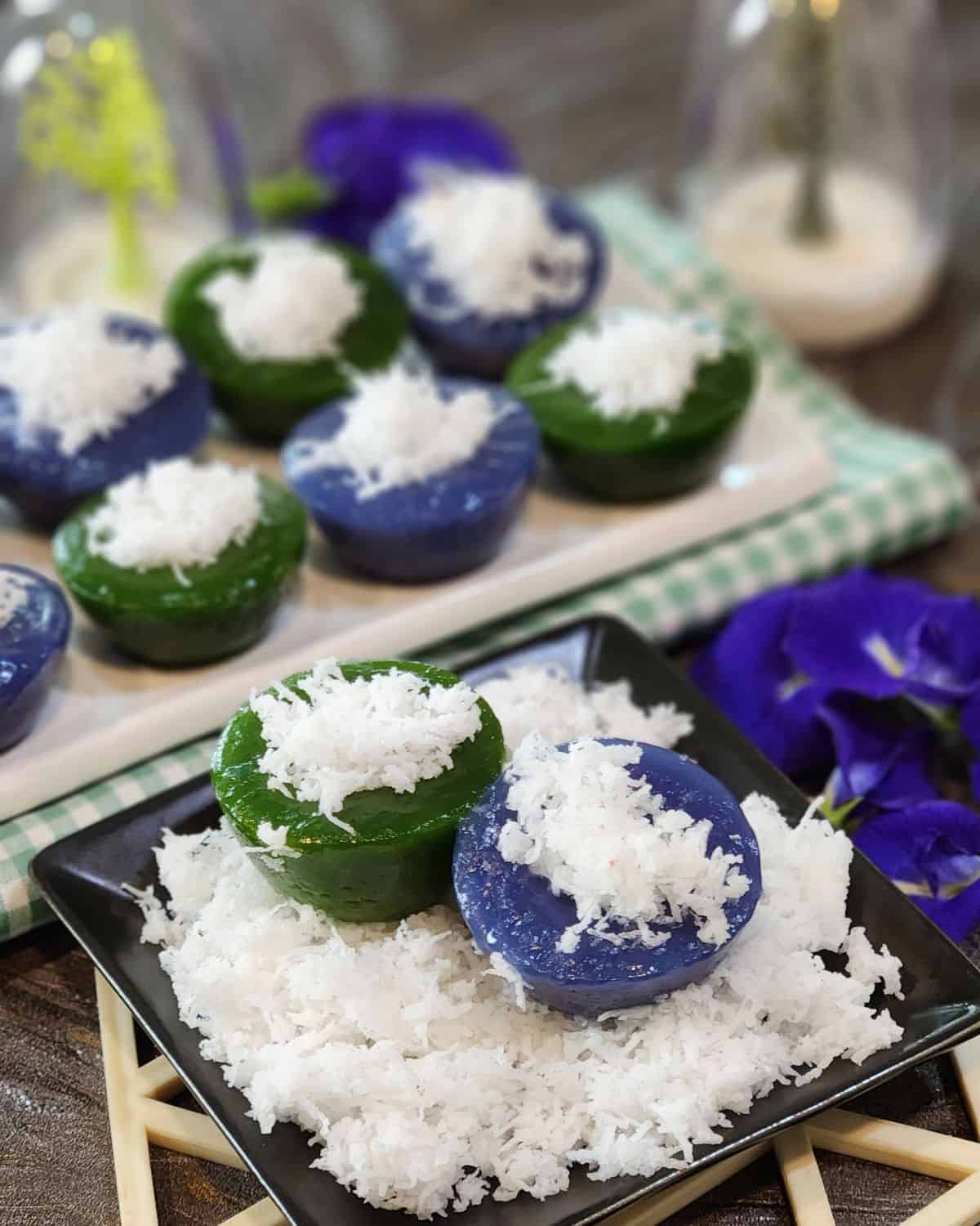 A close up photo of two color Kuih Kosui on steamed grated coconut.