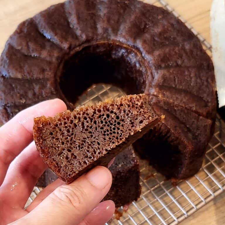 A hand holding a slice of Malaysian honeycomb cake with its beehive-like texture.