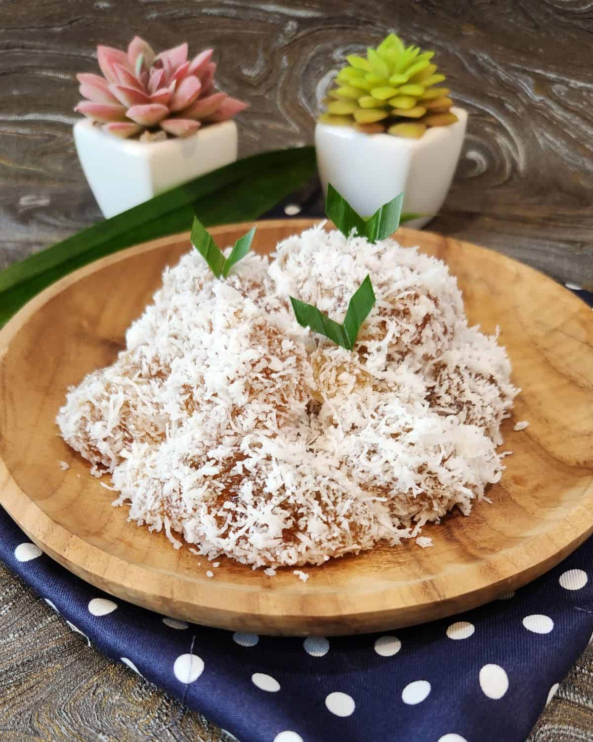 A wooden plate with ongol ongol covered with coconut.