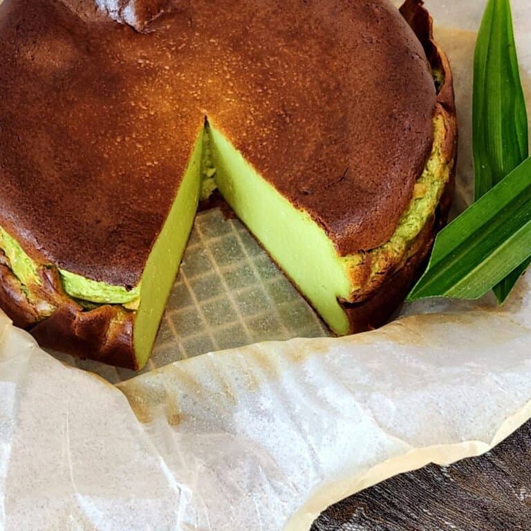 A photo of pandan cheesecake with one slice cut out.