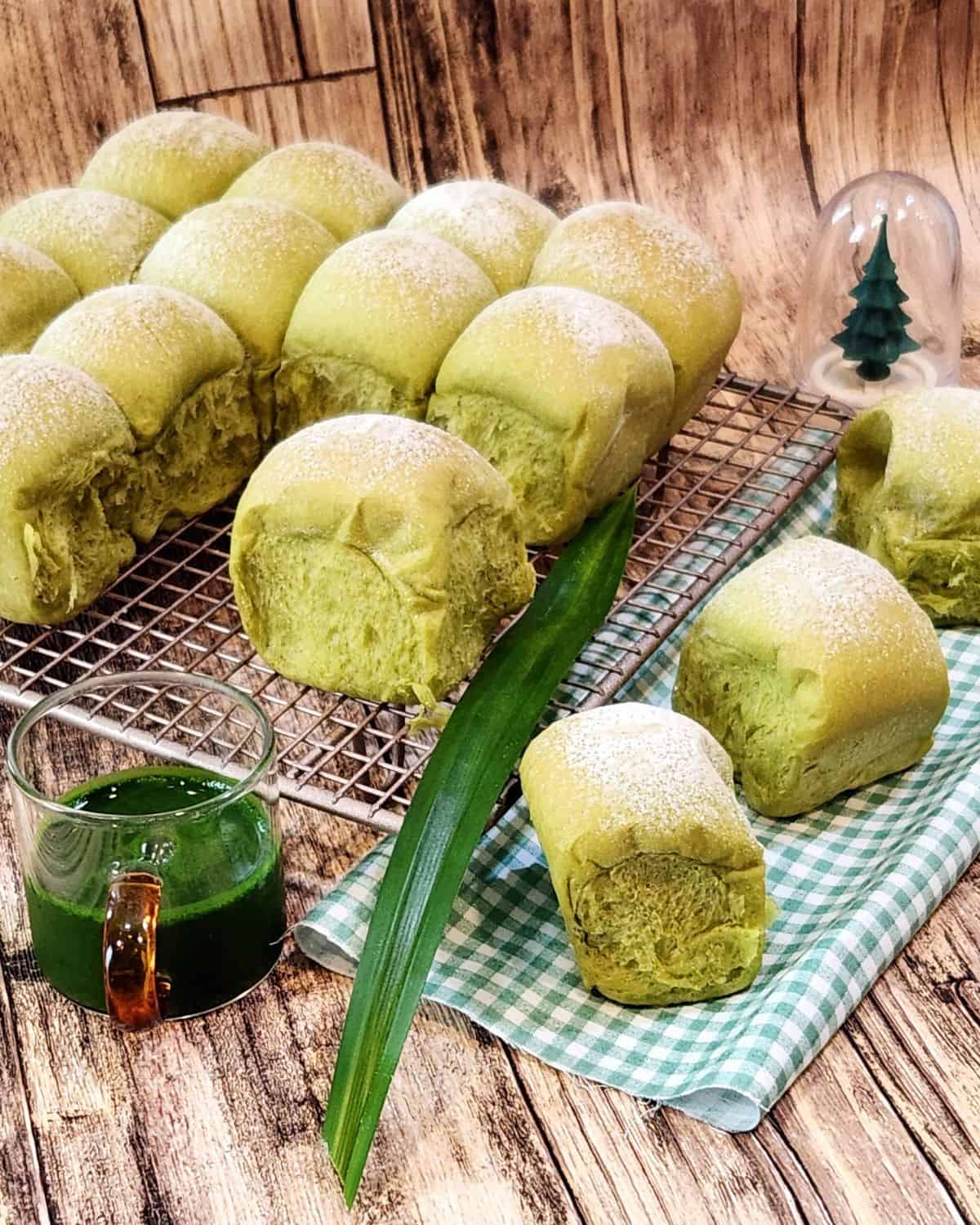 Pandan milk bread on a cooling rack and some pandan extract in a small cup.