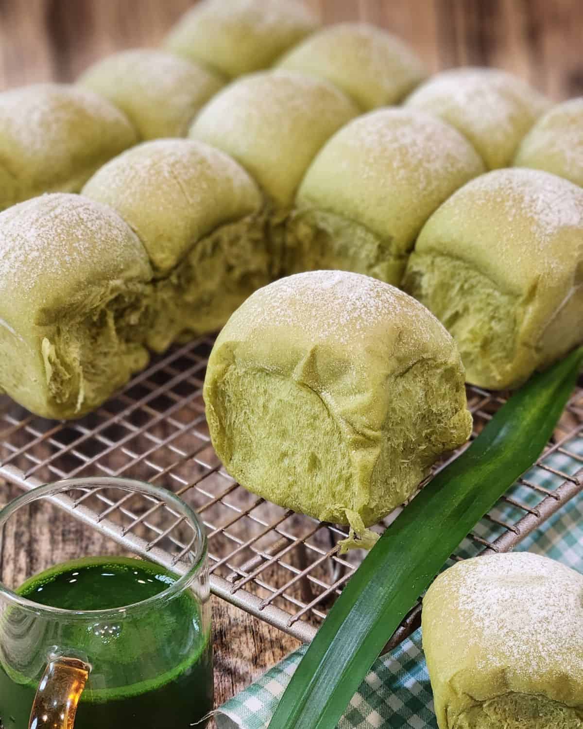 Pandan milk bread on a cooling rack and some pandan extract in a small cup.