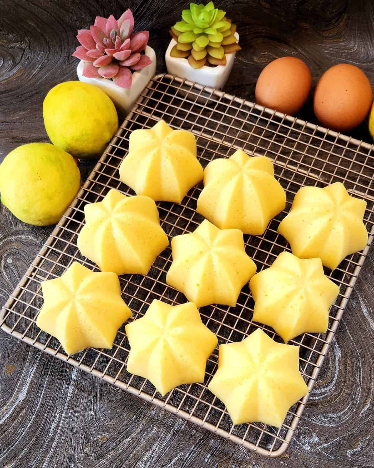 Mini Lemon Cakes on a cooling rack next to lemon and eggs.