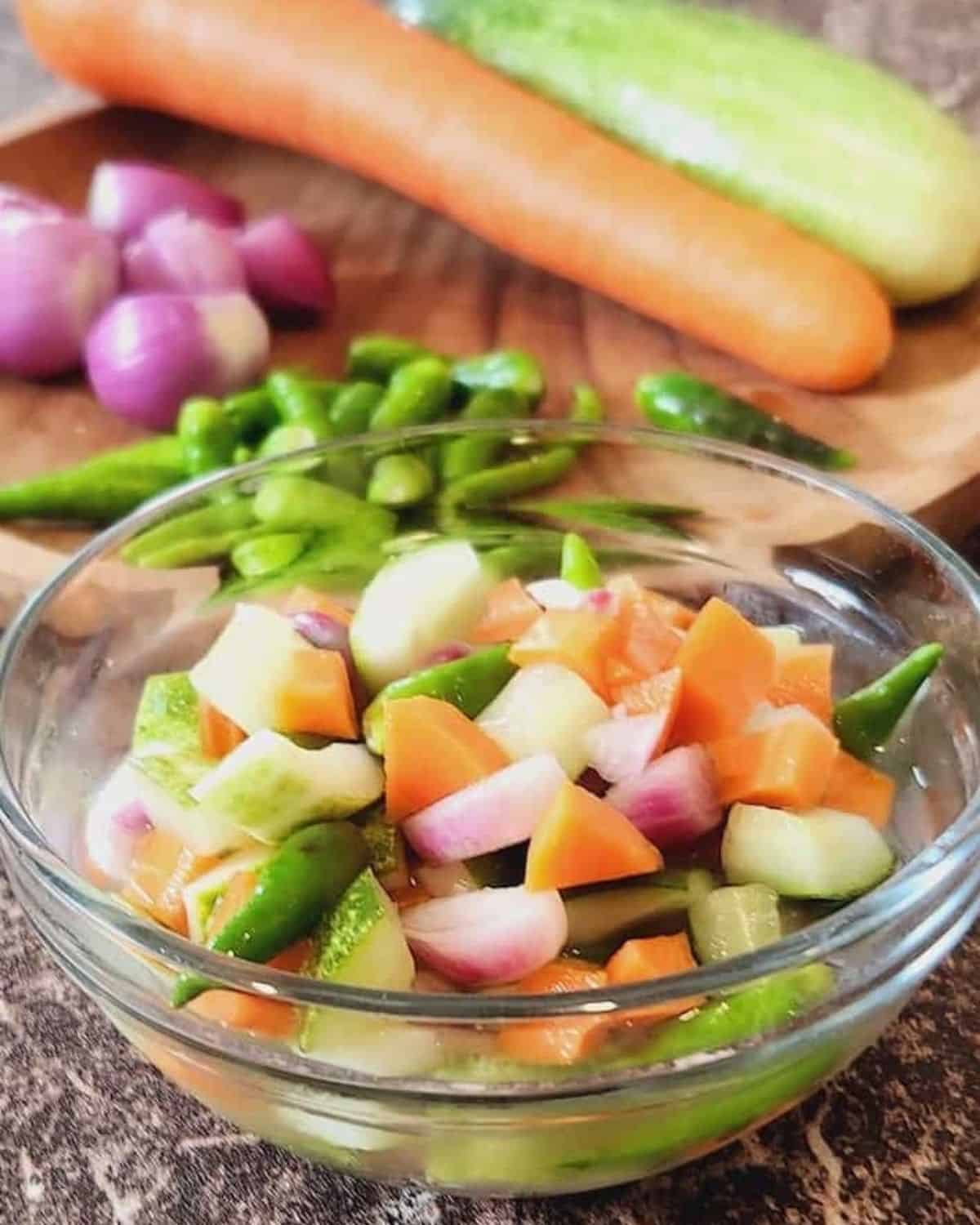 A bowl of acar timun with carrots and green chilis.