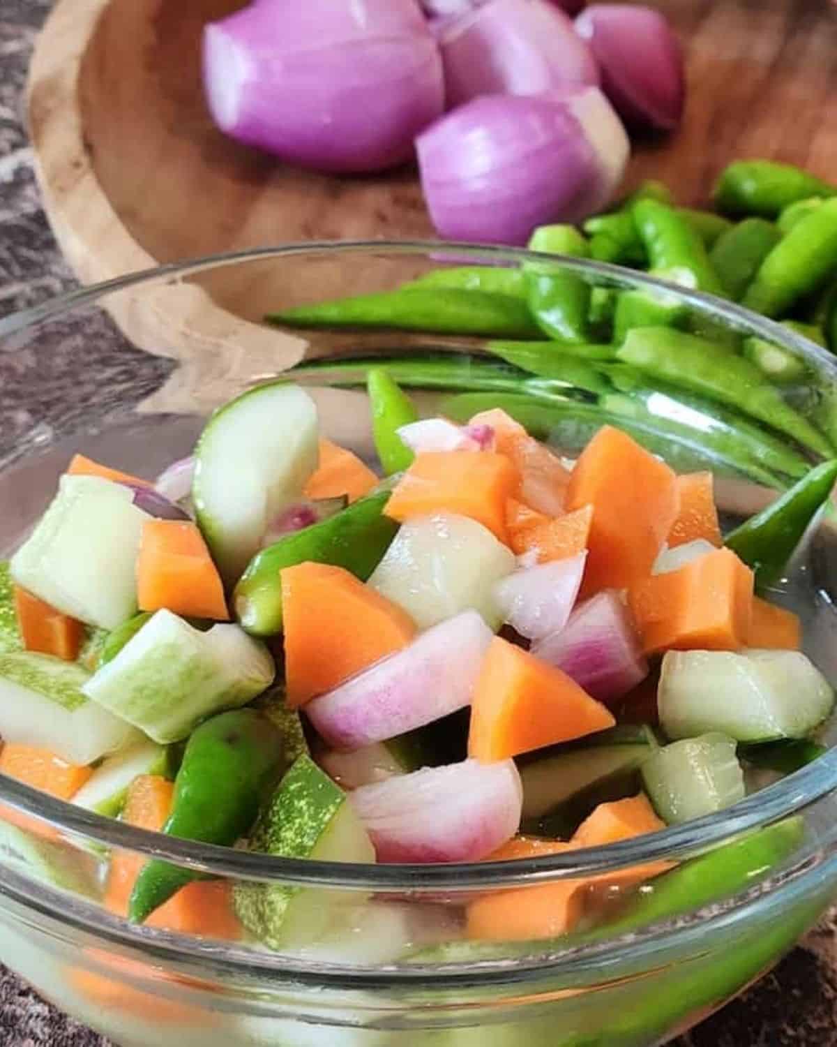 A bowl of acar timun with carrots and green chilis.