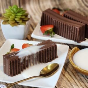 A plate of gluten free chocolate pudding with milk sauce, strawberries, and a spoon.