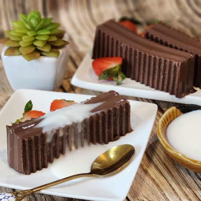 A plate of gluten free chocolate pudding with milk sauce, strawberries, and a spoon.
