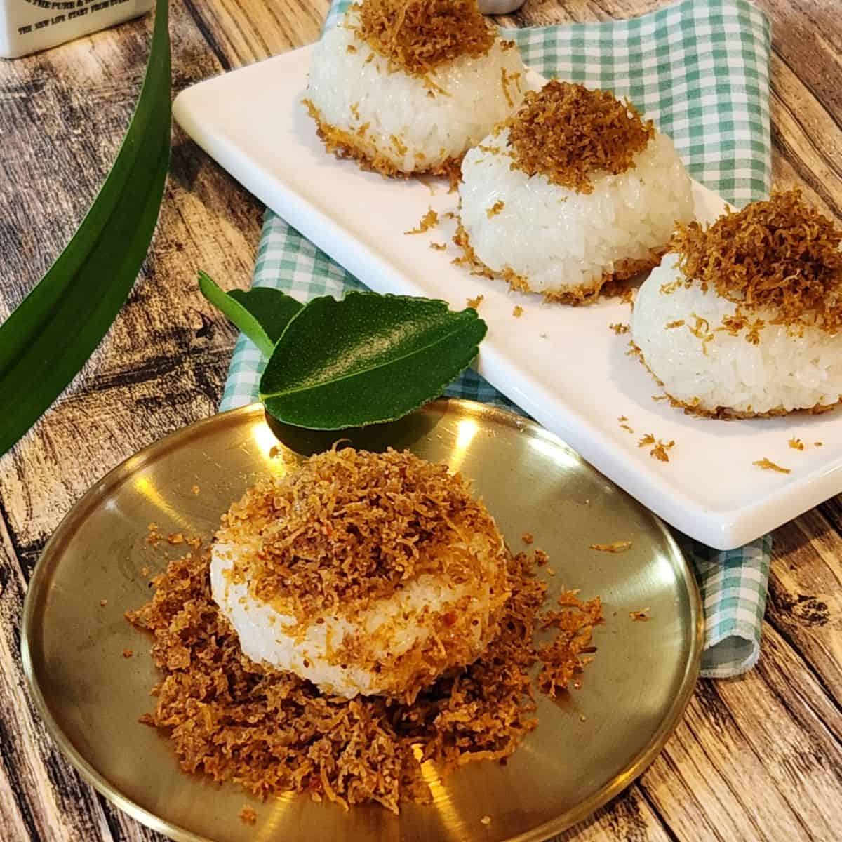 A plate of ketan serundeng with lime leaves and pandan leaves decoration.