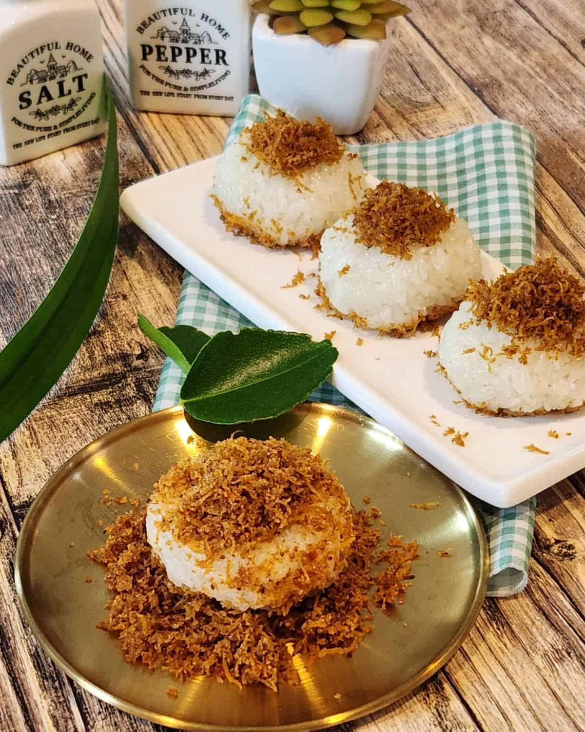 A plate of ketan serundeng with lime leaves and pandan leaves decoration.