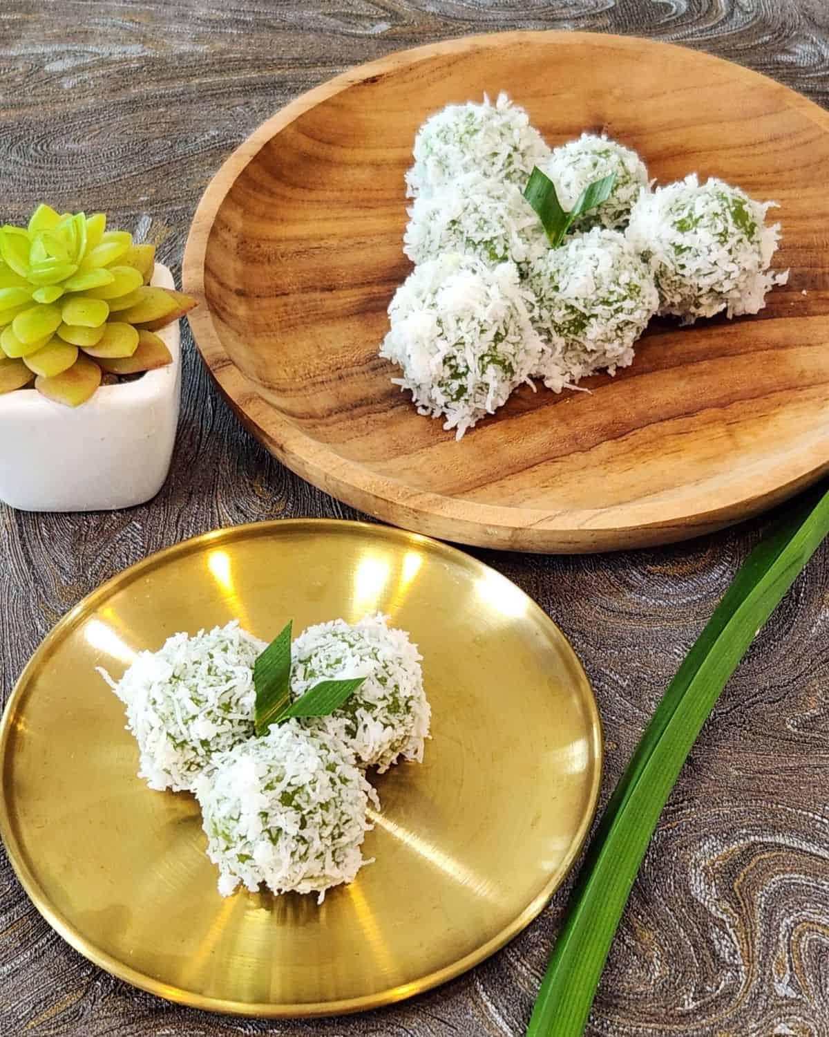 A golden plate with three onde onde and a wooden plate with six klepon.