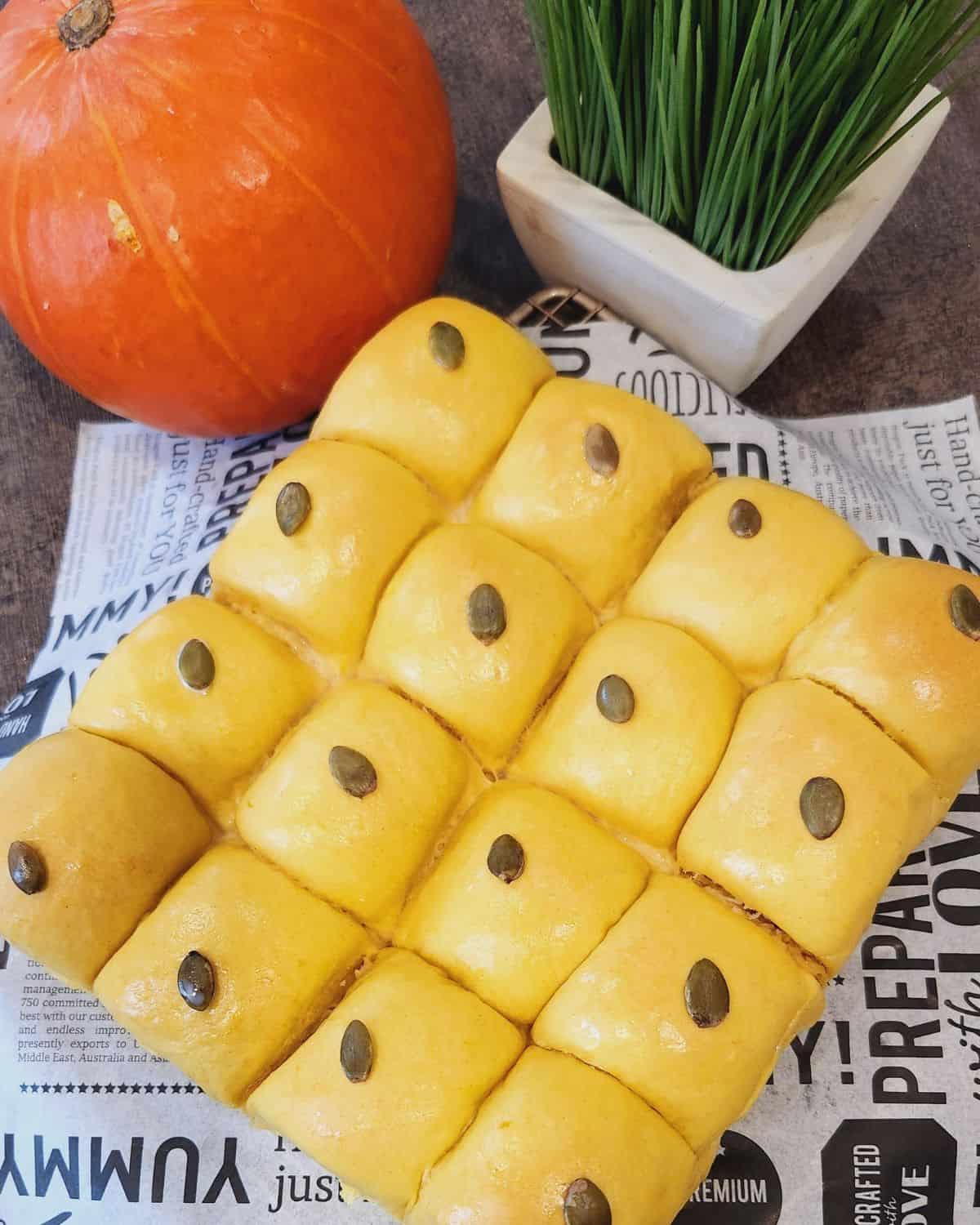 Pumpkin coconut bread on a parchment paper with a pumpkin next to it.