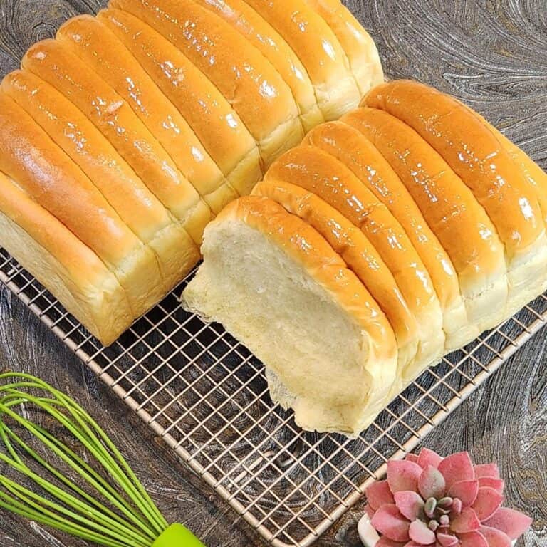 Two loaves of roti sisir on a cooling rack.