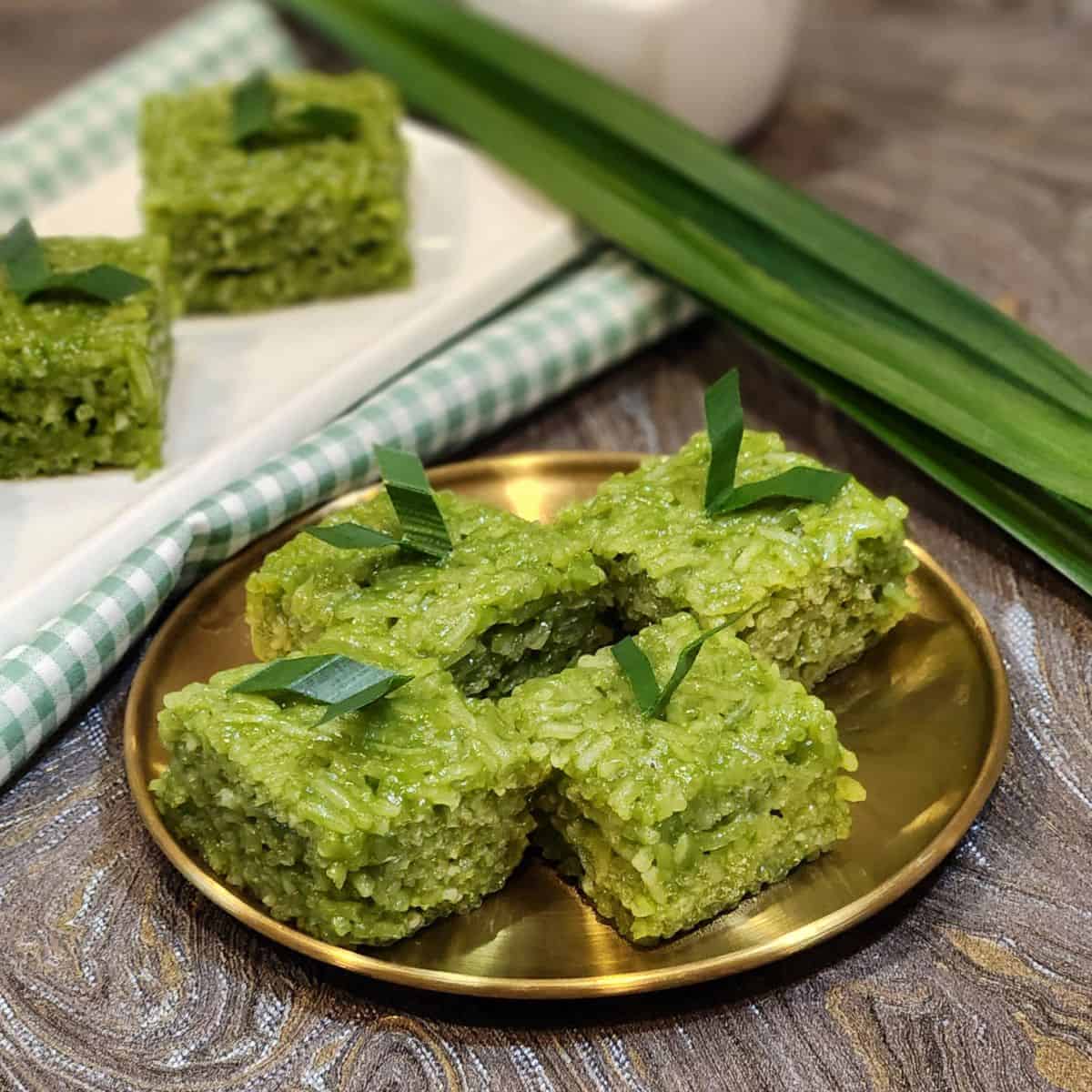 A golden plate with pandan wajik and pandan leaves decoration.