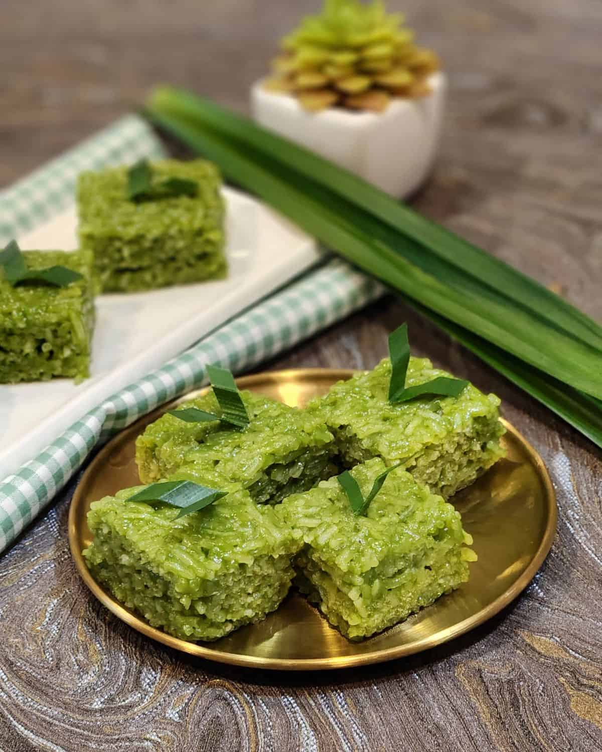 A golden plate with pandan wajik and pandan leaves decoration.