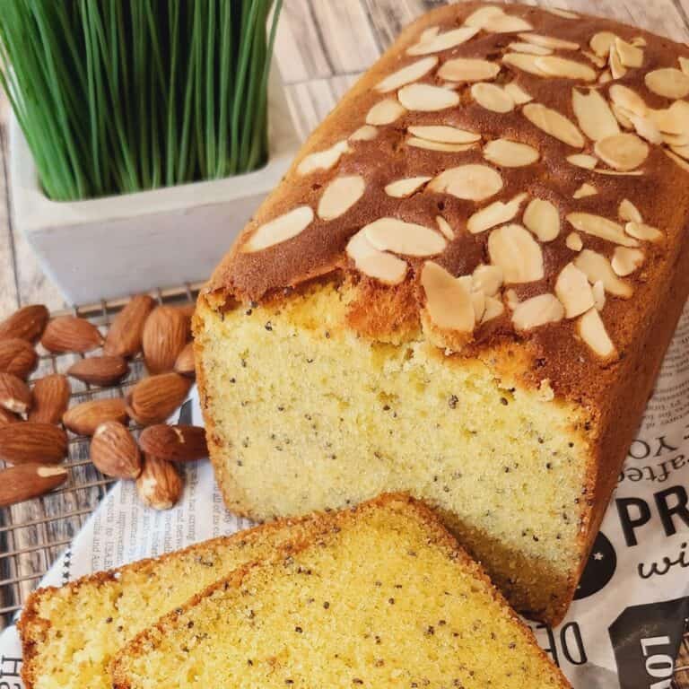 A loaf of Almond Butter Cake with some cake slices on parchment paper.