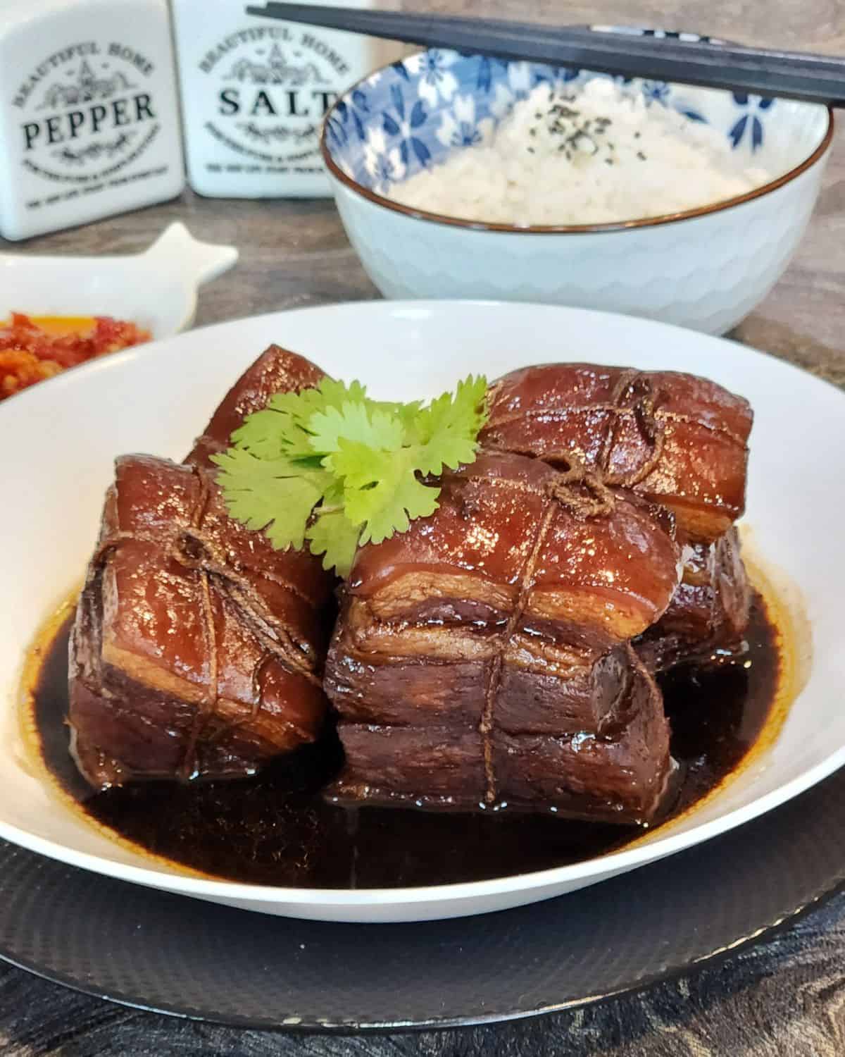 Four slices of Dong Po Rou with coriander leaves.