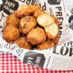 Shrimp balls in a basket with parchment paper on a red and white table cloth.
