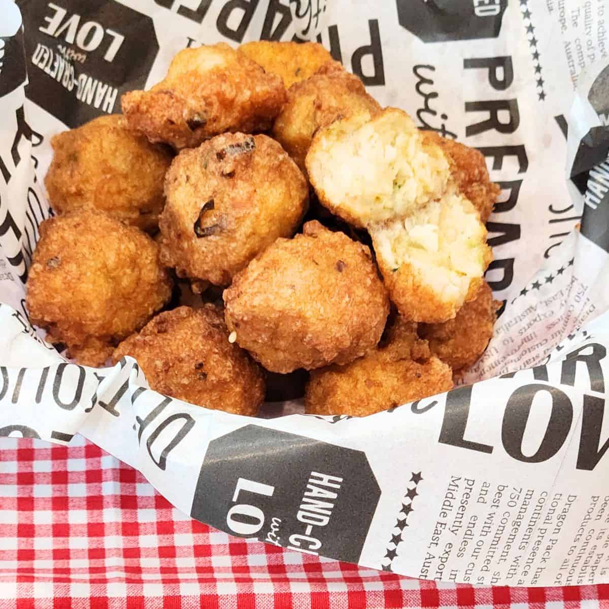 Shrimp balls in a basket with parchment paper on a red and white table cloth.