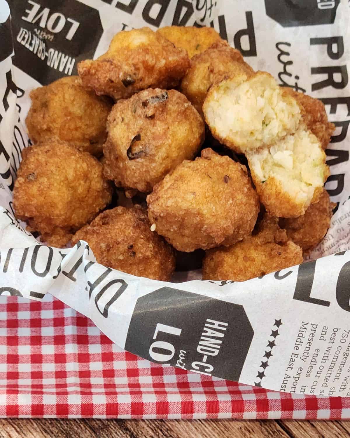 Shrimp balls in a basket with parchment paper on a red and white table cloth.