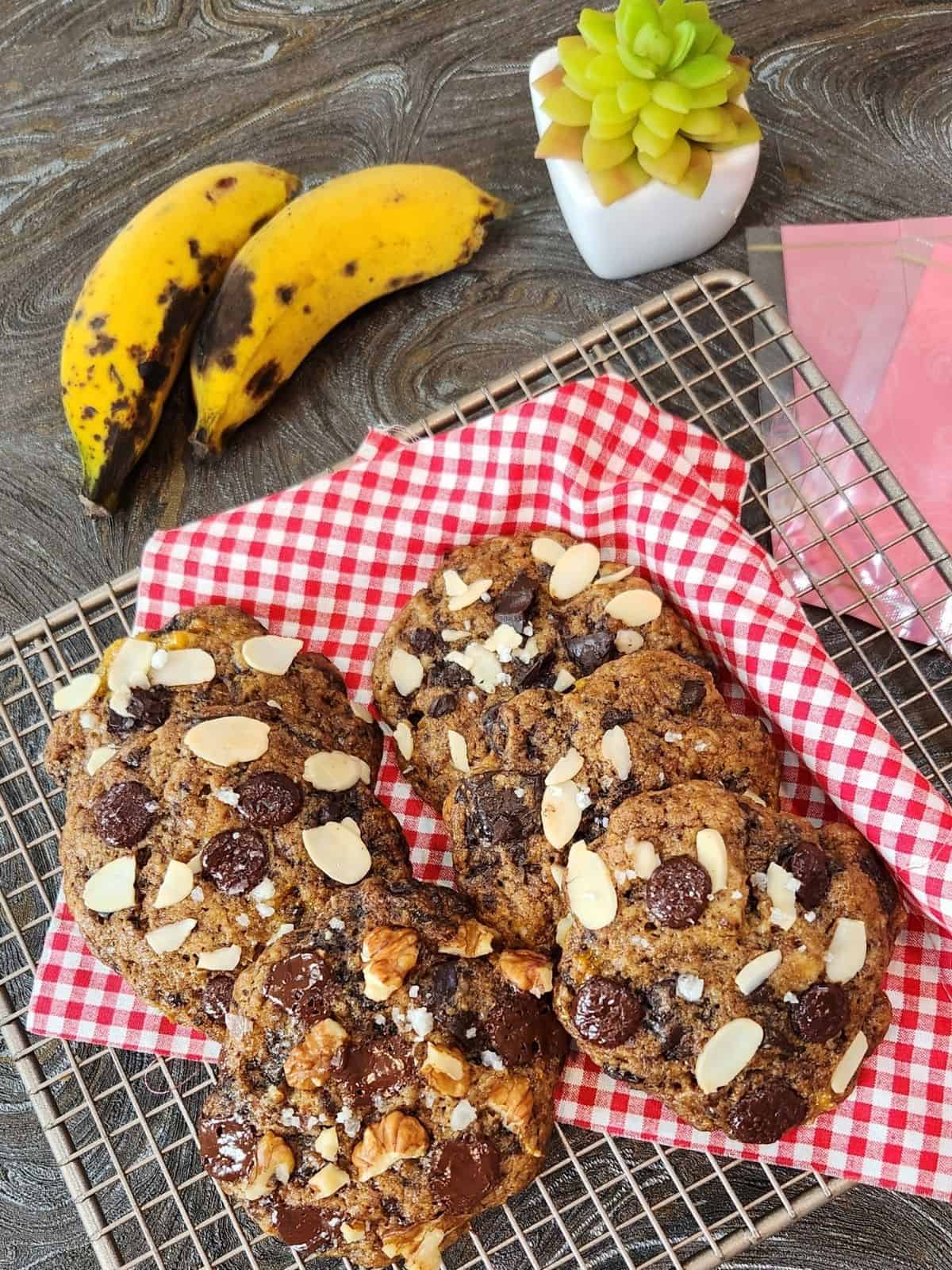 Several banana almond soft cookies on red and white cloth on a wire rack.