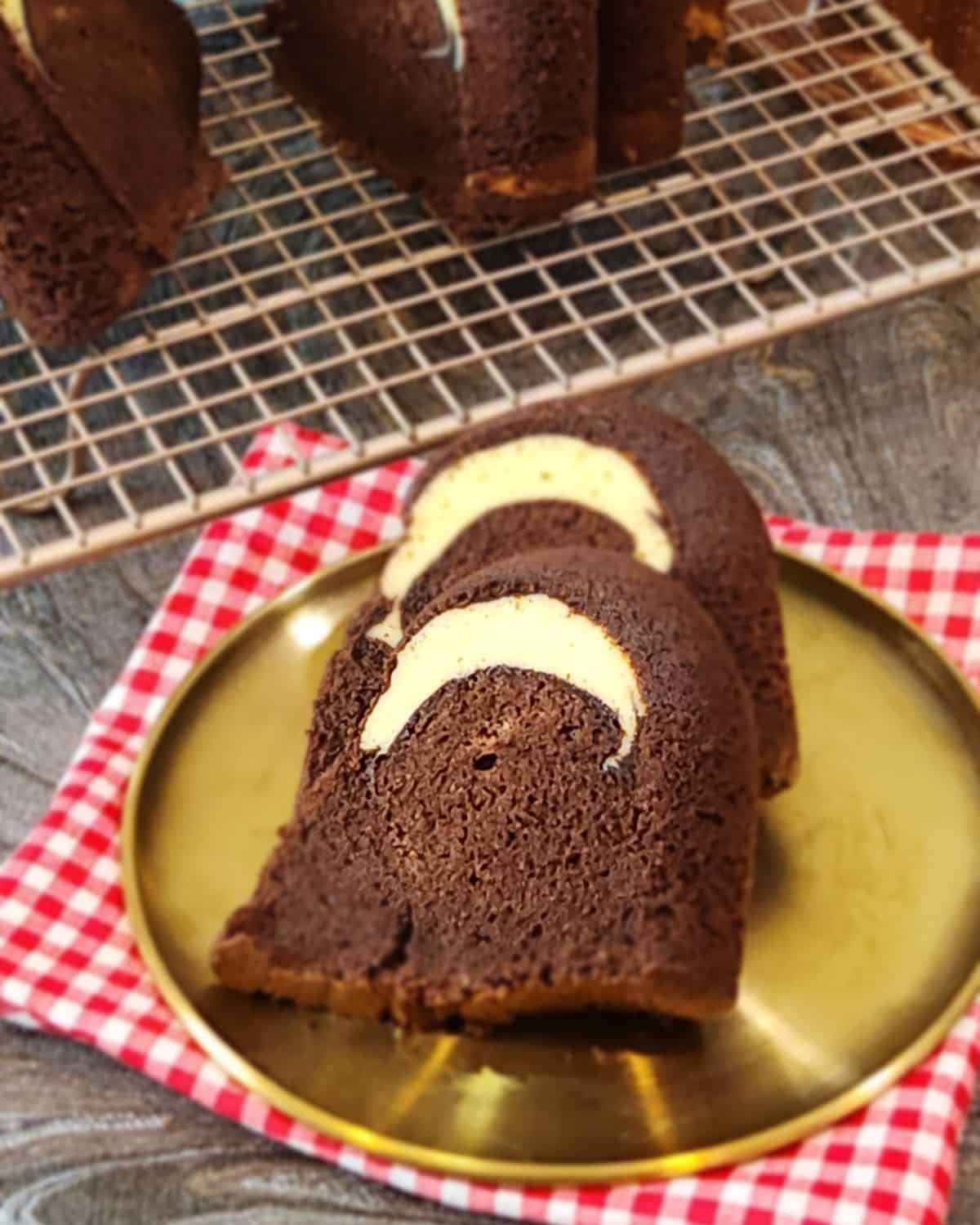 Two slices chocolate cake with cream cheese filling on a golden plate.