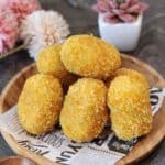 A few krokets or Dutch croquettes on a parchment paper and wooden plate.