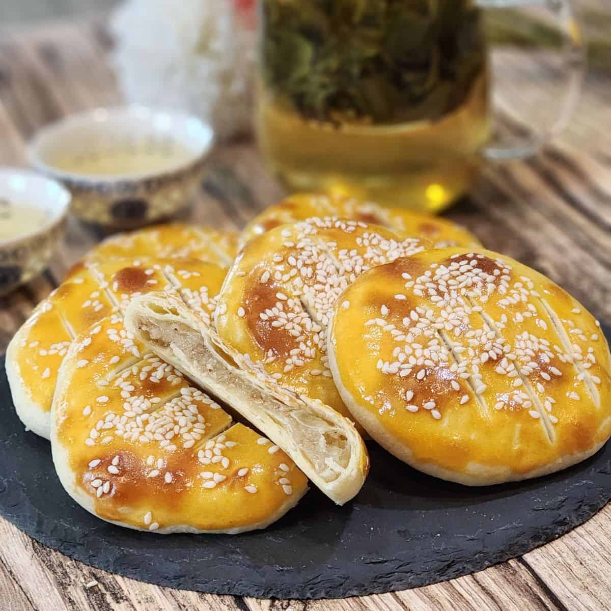 Several wife cakes on a black stone plate with one sliced.