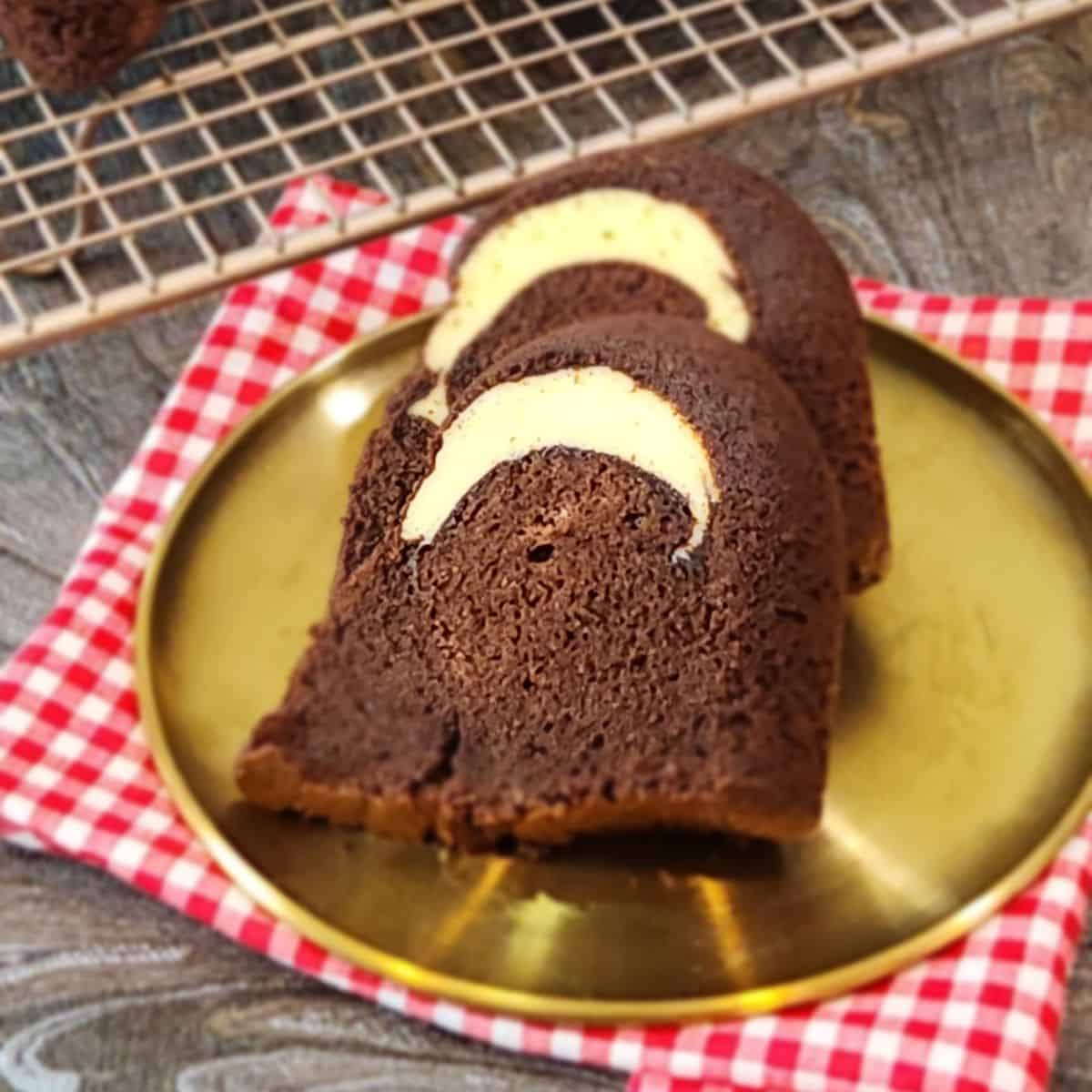 Two slices of chocolate cake with cream cheese filling on a golden plate.