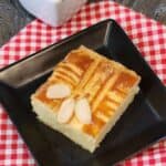 A slice of Dutch butter cake or boterkoek on a black plate and on a red white cloth.