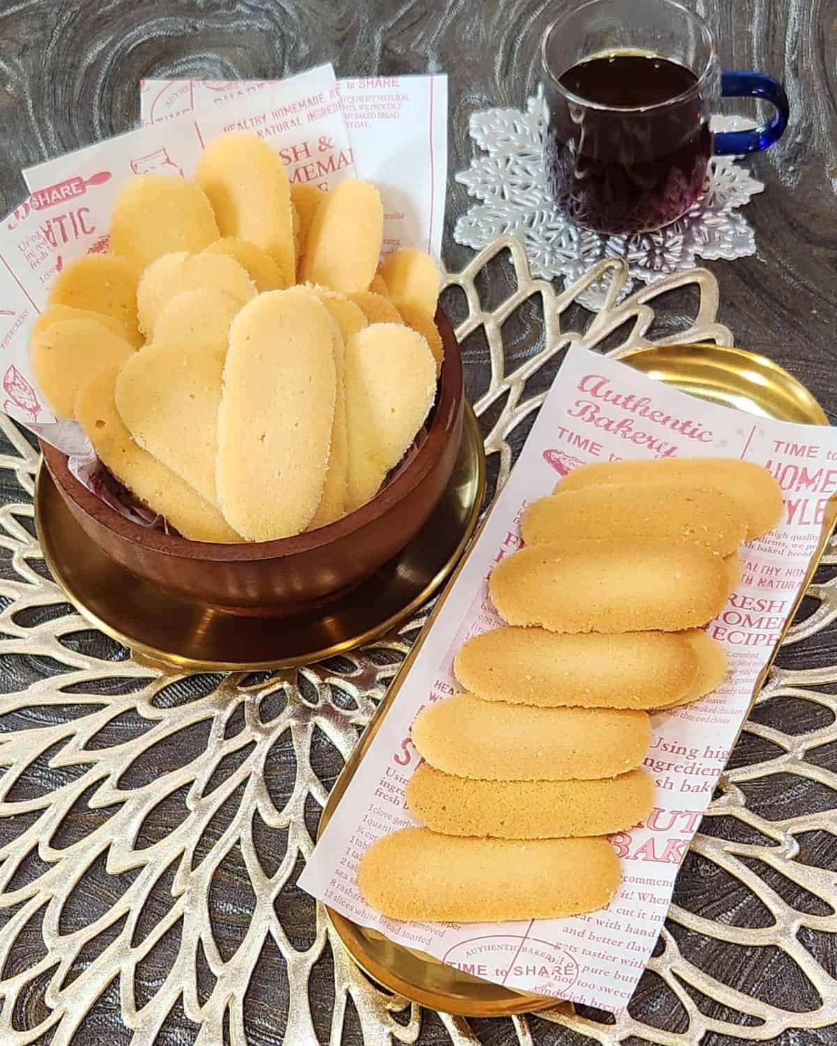 A bunch of cat tongue cookies on a plate and a bowl.