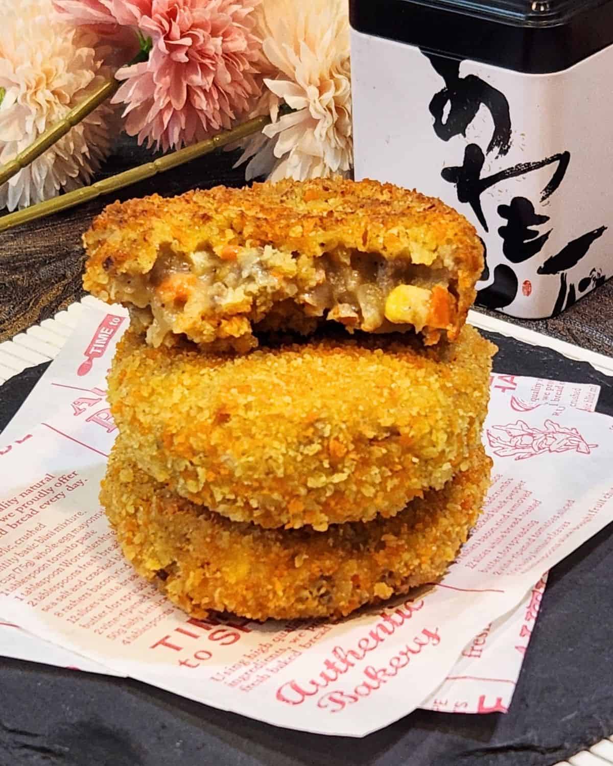 A stack of Japanese croquettes with one that is already sliced. 